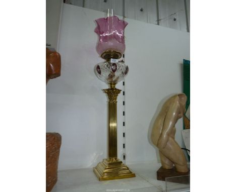 A Brass Oil lamp with Corinthian column base, clear reservoir with ruby glass panels and cranberry glass shade (shade cracked