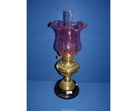 A Brass Oil Lamp having a cranberry glass shade and clear glass chimney.