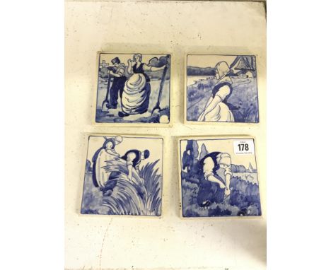 A set of four early 20th century Poole Pottery blue and white tiles decorated in Dutch scenes designed by Joseph Roelants.