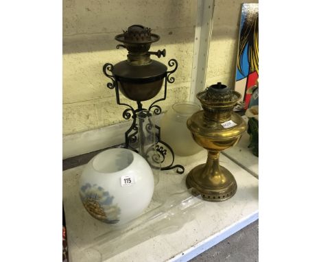 A wrought iron and copper oil lamp base together with a brass oil lamp and various shades.