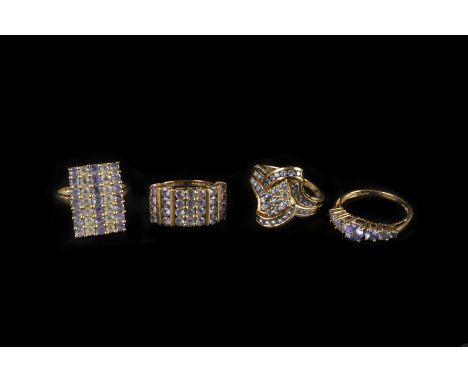 Four modern 9ct gold and gem set dress rings, including a large example with columns of light blue stones, a seven stone ring