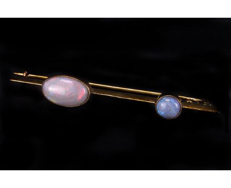 A vintage opal bar brooch, the yellow metal mount set with a circular and an oval polished opal