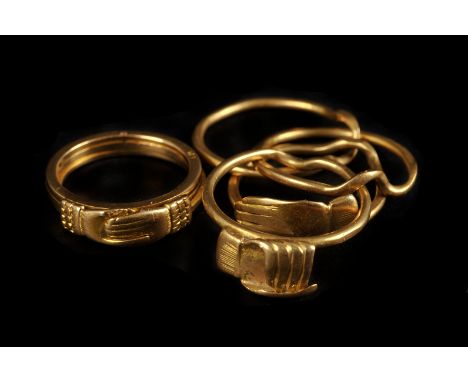 Two vintage yellow metal friendship rings, one being a puzzle ring with four interlocking bands, the other a band also with h
