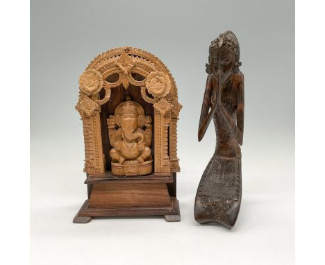 Carved sandalwood Ganesh shrine with ornate floral design atop a dark wood altar 5"L x 2.5"W x 8.75"H and praying intricately