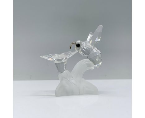 A beautiful clear crystal figurine of a bumblebee with black crystal eyes and rhodium antennas, lying on a frosted branch, po