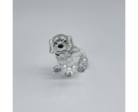Made of clear crystal, with black eyes and nose. Around the dog's neck is a band of elastic which holds a clear crystal keg i