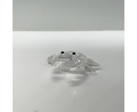 A tiny clear crystal crab standing cautiously, with its pincers out and ready to strike, its black crystal eyes gleaming. Swa