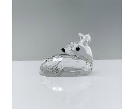 A clear crystal baby deer lies on its stomach with its head turned to the side, adorned with black crystal eyes. Swarovski ba
