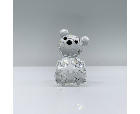 A clear crystal bear sitting on its bottom with paws resting on its chest, adorned with black crystal eyes. Swarovski backsta