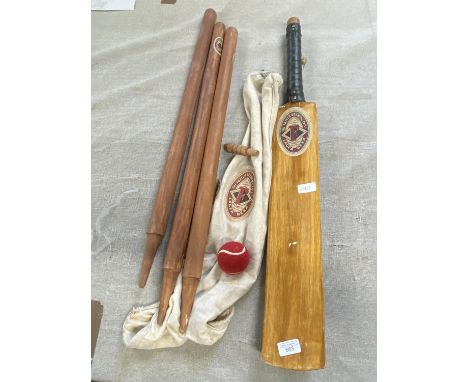 A cricket bat with stumps and bails, shipping unavailable