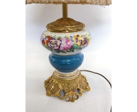 A table lamp mounted on a gilt decorated base with painted or printed floral design to the reservoir