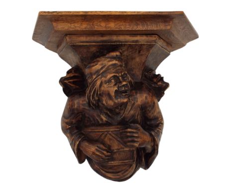 An 18/19th century carved corbel in the form of a musician playing a Psaltery type instrument wear a chaperon, with later add