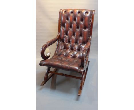 A 20th Century mahogany rocking chair with scroll arms and red leather button back upholstery