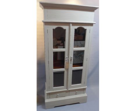 A grey painted teak bookcase with two glazed doors above two drawers raised on bracket base, H:180cm W:83cm D:36cm