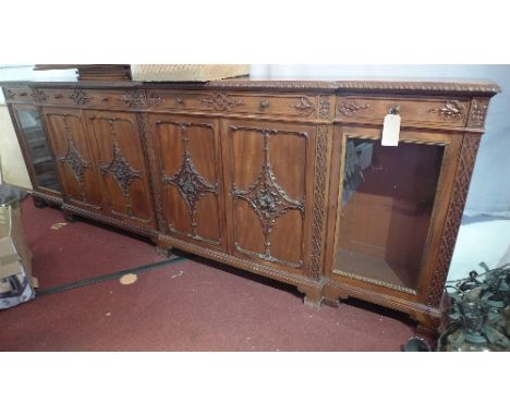 A Chippendale style breakfront side cabinet with four drawers above four carved cupboard doors flanked by two glazed doors, r