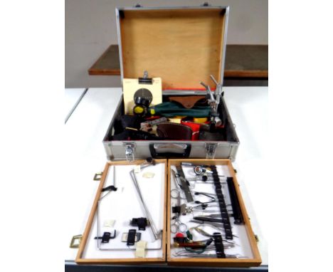 An aluminium case containing shooting equipment to include gun cleaning rods, precision tools, a porta-aim chin rest, glasses