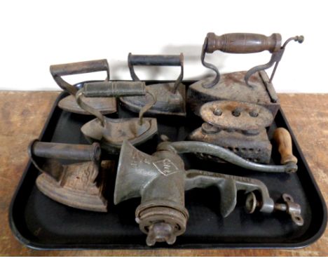 A tray containing seven antique cast iron flat irons together with a vintage mincer 