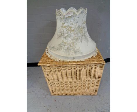 A large wicker hamper together with a standard lamp shade 