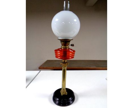A Victorian brass Corinthian column oil lamp with red glass reservoir, chimney and shade 