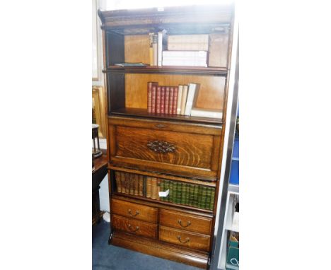 A GLOBE-WERNICKE STYLE OAK BOOKCASE with three leaded glass sections, central secretaire and four drawers below