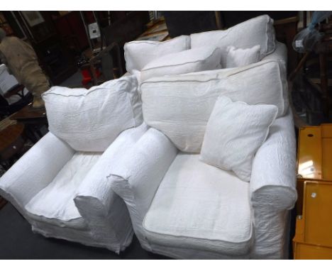 A THREE PIECE LOUNGE SUITE including two seater sofa , two armchairs and a pouffe, in white loose covers