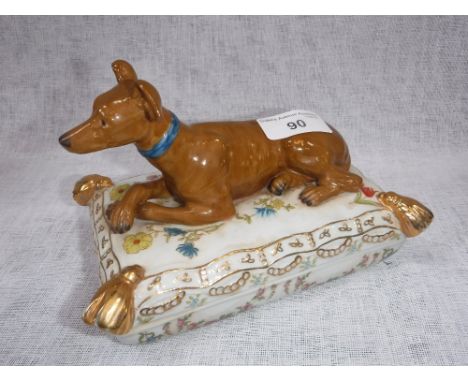 A CERAMIC BOX AND COVER in the form of a Whippet on a cushion