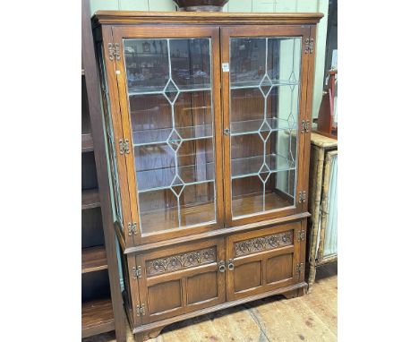 Old Charm display cabinet having two leaded glazed doors above two carved panel doors, 161cm by 107.5cm by 39cm.