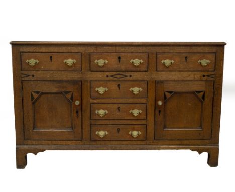 An early 19thC Anglesey or North Wales dresser base, with beaded plain top and an arrangement of three frieze drawers, over t