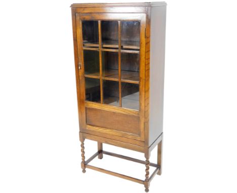 A 1920's oak display cabinet, with glazed door, on barleytwist legs joined by a front block stretcher, 140cm H, 62cm W, 30cm 