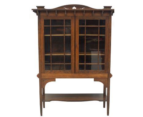 A late Victorian Arts and Crafts display cabinet, with pierced back to an over hang top with supports, over two plain astraga