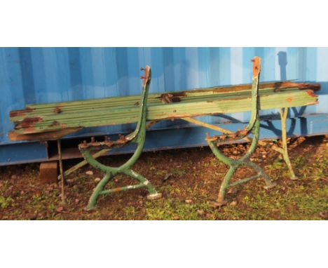 An early 20thC cast iron and wooden slatted railway type bench, partially painted green, 173cm W.  (dilapidated)
