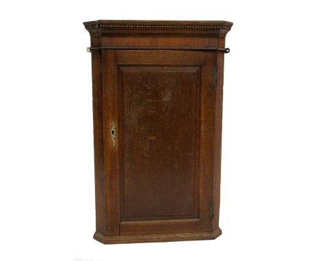 A George II oak hanging corner cupboard, with ebony and boxwood faux dentil molded cornice, single fielded panel door reveali