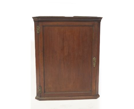 A George III mahogany hanging corner cupboard, with moulded cornice, single panelled door with brass escutcheons and H hinges