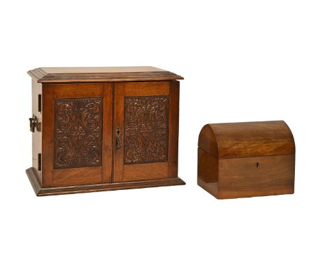 A Victorian oak smoker's cabinet, with carved panelled doors and brass handles, the fitted interior with earthenware tobacco 