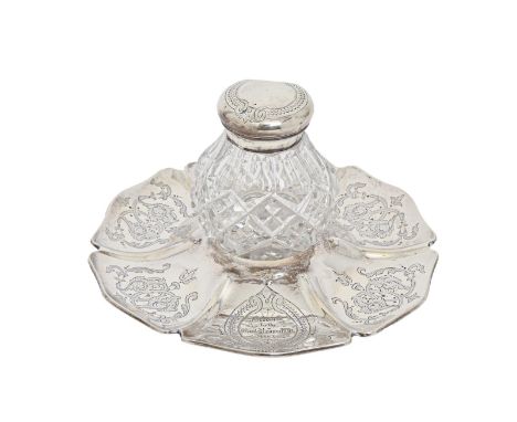 A Victorian silver mounted cut glass inkwell and stand, engraved with foliate scrolls and inscribed Presented by the Earl Bro