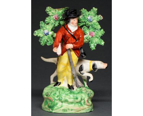 A Staffordshire earthenware figure of a sportsman, c1830, standing before his dog, gun and flask in hand, on bright green mou