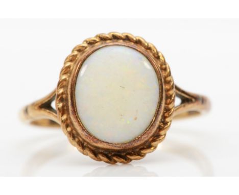 A 9ct gold opal dress ring, with rope twist boarder, flashes of red, blue and green, U, 3.4gm.Condition report - the top of t