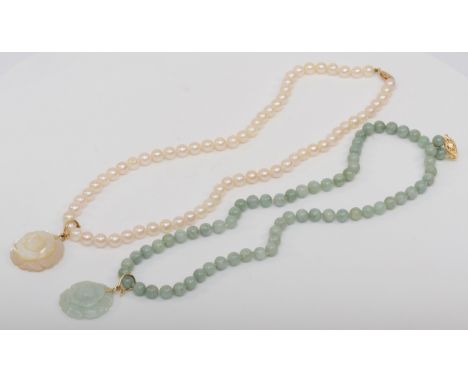 A 14k gold clasped jade beaded necklace and carved floral pendant, 24mm, together with a matching pearl example. 