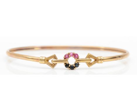 A 9ct gold ruby and sapphire bangle, internal 59mm, 4.6gm. 