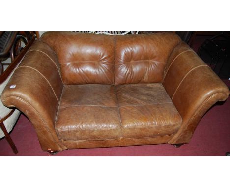 A contemporary tan leather two seater scroll end sofa, raised on turned squat supports, width 163cm