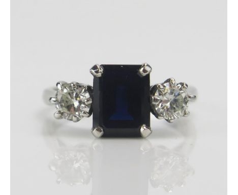 An 18ct White Gold, Sapphire and Diamond Three Stone Ring, c. 8.5x6.6mm emerald cut and 4.57mm round brilliant cuts, size M, 
