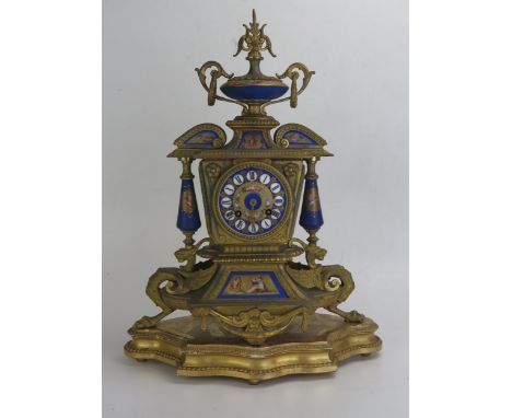 A 19th century French gilt metal and porcelain mantel clock, surmounted with a twin handled urn and cover, having a 9cm porce