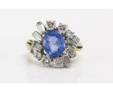 An 18ct Gold, Sapphire and Diamond Cluster Ring, c. 9.1x7.4mm pale blue principal stone, surrounded by 4 c. 3.4mm and 4 c. 2.
