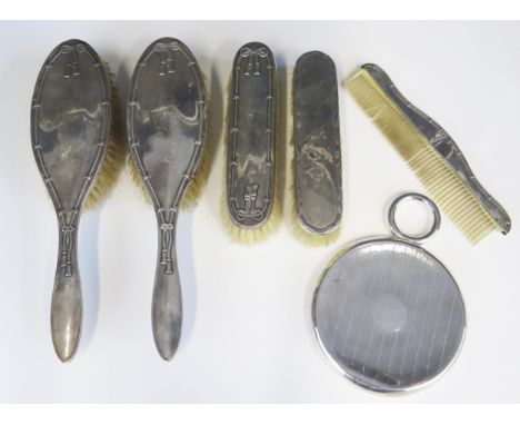 A silver backed five piece dressing table set includes two hair brushes, two clothes brushes and ivorine comb, together with 