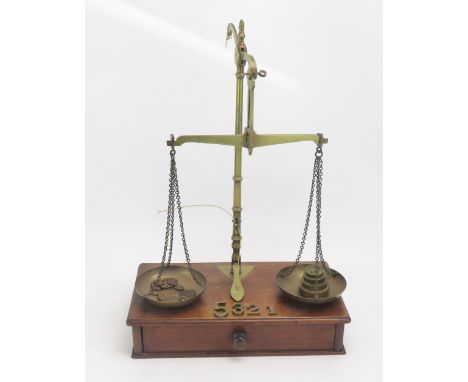 A pair of brass balance scales on a mahogany base with single frieze drawer containing assorted weights. 33cm wide, 41cm high