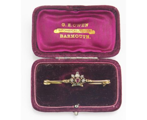 An Antique Ruby, Emerald and Rose Cut Diamond Bar Brooch with a central crown form in a high carat precious yellow metal sett