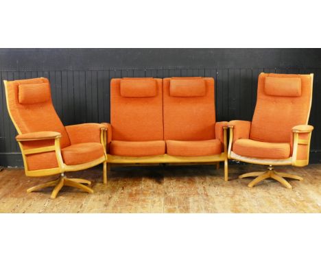 An Ercol Three Piece Suite in salmon pink with twin swivel armchairs 