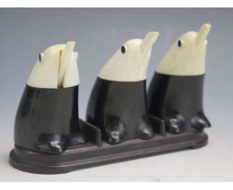 A vintage Bakelite three piece condiment set in the form of penguins, on an associated Bakelite stand.