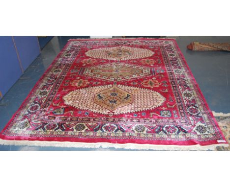 Indian carpet with three cream lozenges on a red ground, 354cm x 274cm.