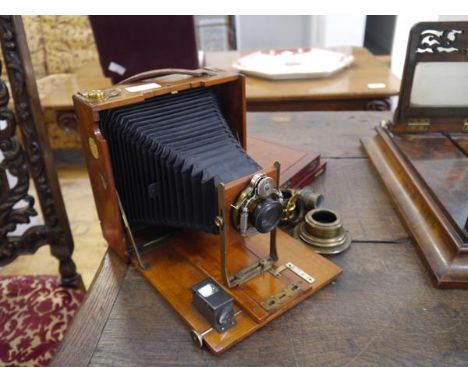An early 20th century folding plate camera, with mahogany case, the shutter signed Bausch & Lomb "with three gilt-brass lense